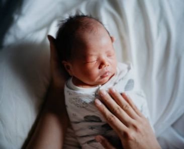 An Asian Chinese mother carrying and putting her newborn baby to sleep