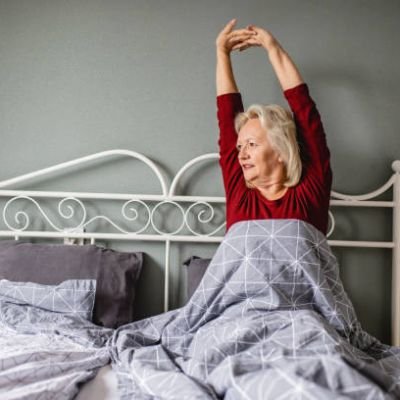 Senior woman wake up and she is stretching in bed